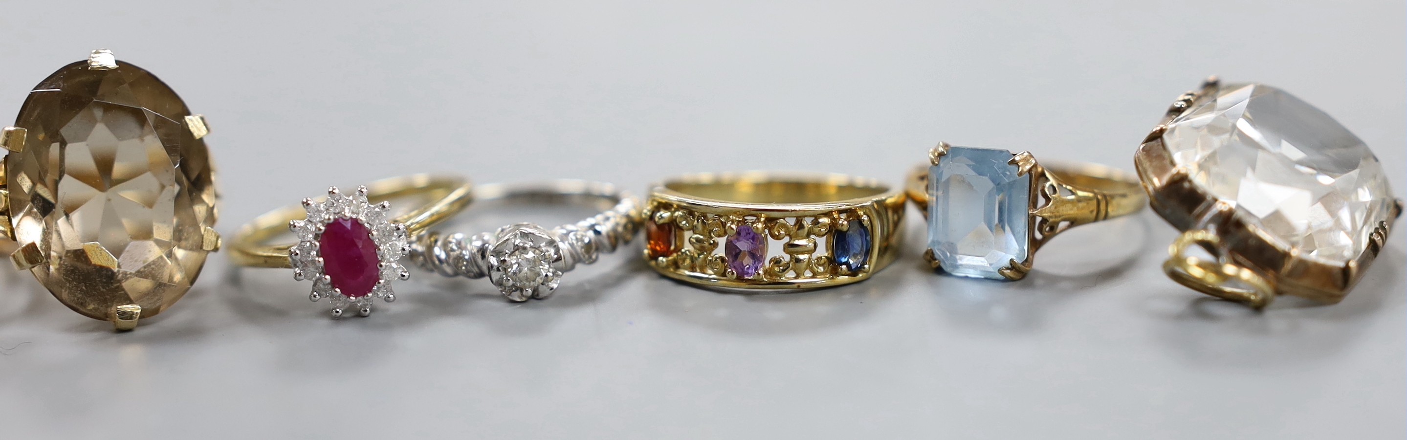 A modern 9ct white gold, blue topaz and diamond set pendant, ten assorted modern 9ct and gem set rings, a yellow metal and opal ring and a quartz set pendant.